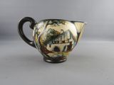 a small pitcher with a painting on it sitting on a table