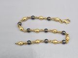 un collier composé de perles dorées et noires, muni d'un fermoir doré