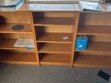 a desk with a book shelf and a chair in front of a window