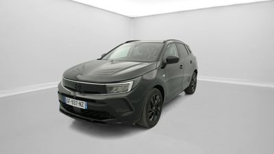 Une voiture noire est garée dans une pièce blanche au sol blanc.