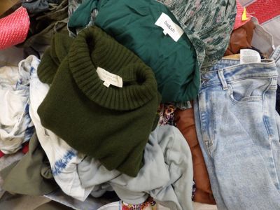 un tas de vêtements posé par terre à côté d'un autre tas de vêtements