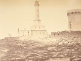 a black and white photo of a lighthouse on top of a hill