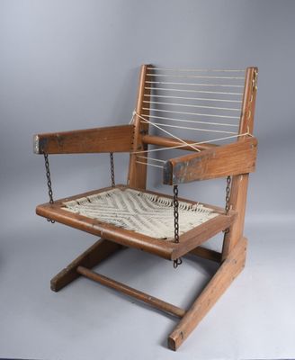 une vieille chaise en bois avec une assise en corde, posée sur un socle