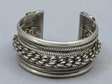 silver cuff bracelet with braid design on top of it