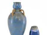 a blue vase with a rope handle next to a blue vase
