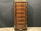 a tall wooden chest of drawers with a marble top