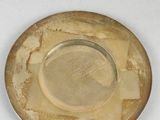 a gold plate with a brown rim sitting on a white surface