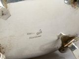 a silver tea pot sitting on a table next to a cup