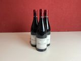 two bottles of wine sit on a table in front of a red wall
