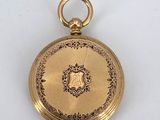 a close up of a gold pocket watch on a white surface