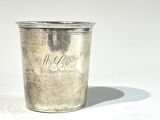 une tasse en argent posée sur une table à fond blanc