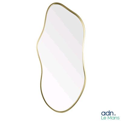 un miroir à cadre doré aux bords incurvés sur fond blanc
