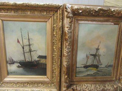 two paintings of ships in gold frames on a table
