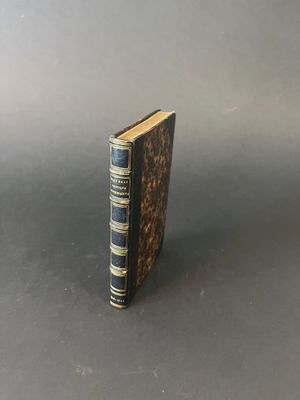 an old book sitting on top of a table next to a gray wall