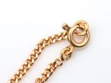 a close up of a gold chain with a clasp on a white surface