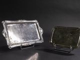 two silver trays with handles and handles on a black surface