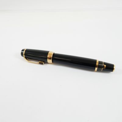 un stylo noir et or posé sur une surface blanche