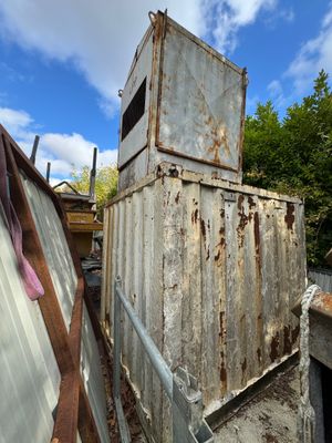 un vieux conteneur métallique posé au sommet d'un tas de ferraille