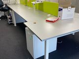 a white desk with a green divider and a black chair in an office