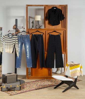 une pièce avec des vêtements suspendus à un portant et une chaise placée devant celui-ci