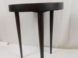 une petite table noire à trois pieds, avec un plateau incurvé