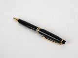 un stylo noir et or posé sur une surface blanche