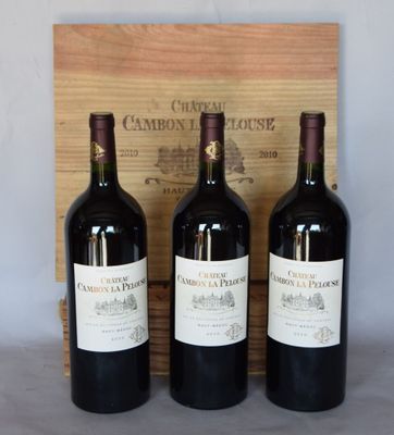 trois bouteilles de vin rouge sont posées devant une caisse en bois