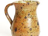 a brown and black pitcher sitting on a white surface