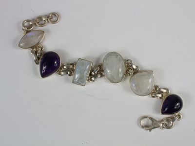 silver bracelet with purple and white stones on it on a white surface