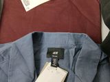 three men ' s shirts and a hat are on a table
