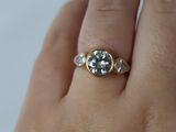 a woman ' s hand holding a ring with a diamond on it