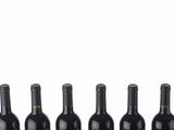 six bottles of wine lined up in a row on a white surface