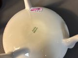a white tea pot with a handle on a table