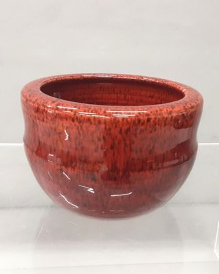 a red bowl that is sitting on a glass shelf