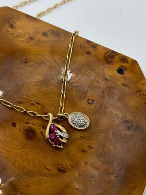 necklace with a gold chain and a red stone on a wooden board