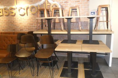 tables and chairs in a room with a brick wall behind them