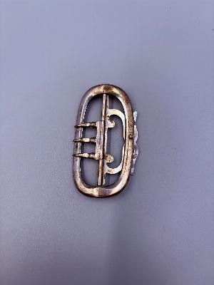 une image représentant une broche en argent sur laquelle figure la lettre « e »