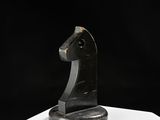 sculpture représentant une tête de cheval sur un socle blanc, sur fond noir