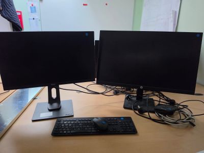 two computer monitors sitting on a desk with a keyboard and mouse
