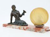 a statue of a woman sitting on a marble block with a lamp on it