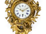 une horloge dorée accrochée à un mur blanc, sur fond blanc