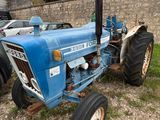 un tracteur bleu garé près d'un mur de briques
