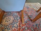 a red and blue rug on the floor next to a mirror