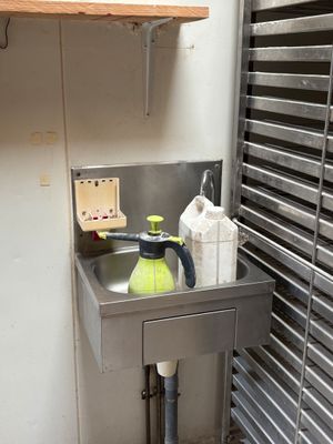 a sink in the corner of a kitchen with a shelf above it