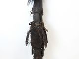 an old wooden figure with black feathers on it ' s head and legs