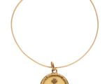 Gros plan sur un collier en or sur lequel se trouve une pièce de monnaie