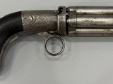 un revolver argenté avec une poignée noire sur une surface blanche