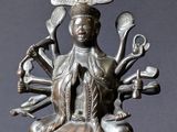 statue en bronze représentant une femme assise dans un bol, entourée de divers objets