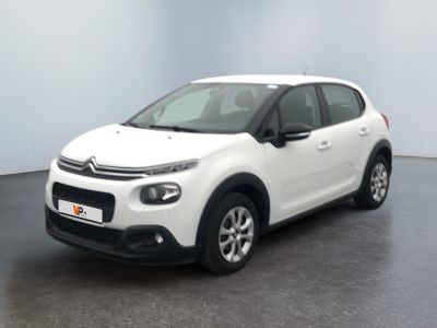 La Citroën blanche est garée dans une pièce au sol noir.