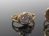 two gold rings with diamonds and a coin on a reflective surface